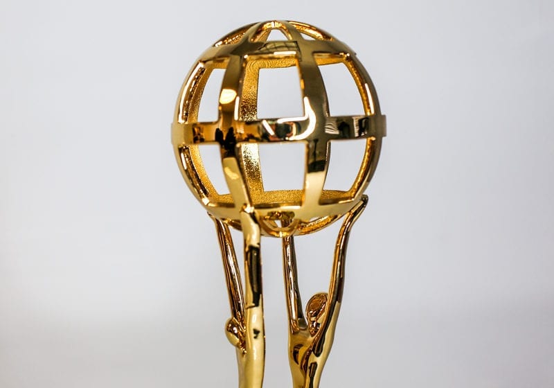 Polished Golden Award Statue Of Two Figures Holding Up A Globe