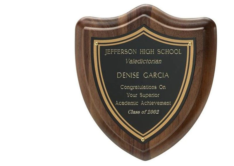 Wooden award plaque cut into the shape of a shield. Metal personalized plate attached to the frontside.